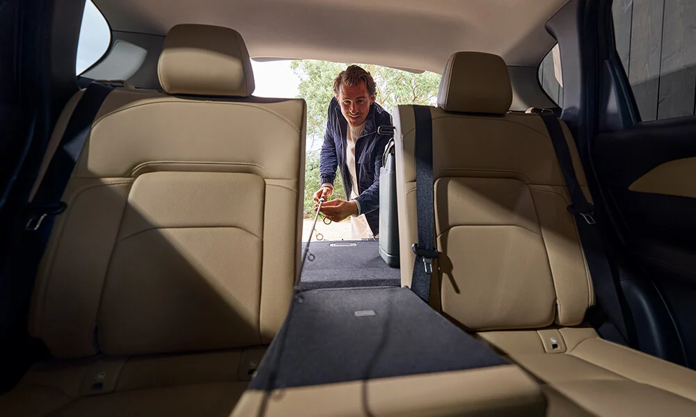 Vue à partir des sièges arrière d’un Mazda CX-5 montrant un homme qui rabat le siège arrière du centre.